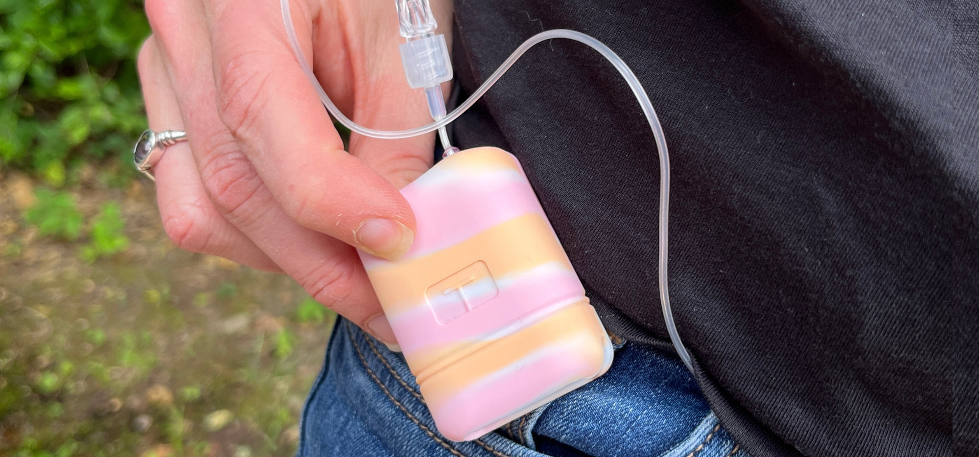 Women holding a Tandem Mobi Insulin Pump in her hand with a Sugar Medical pink, organge and white protective gel skin cover on it.