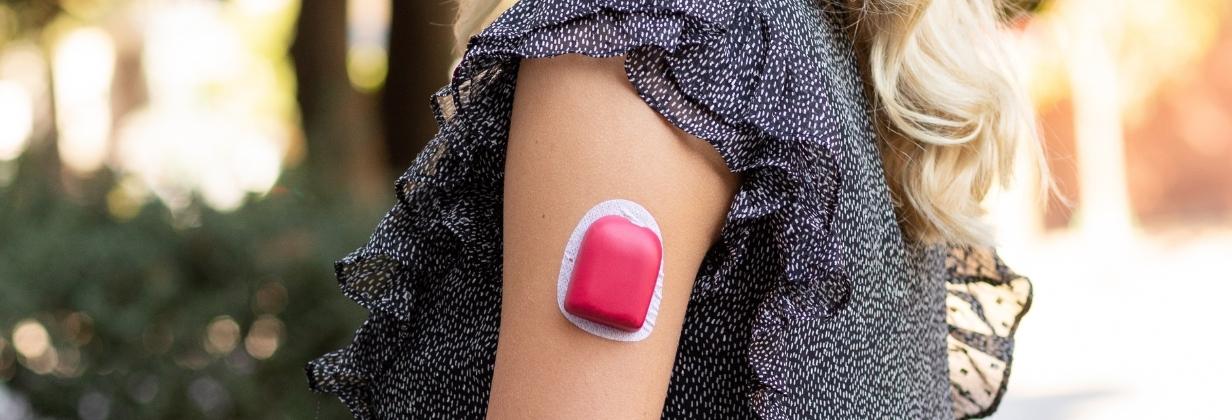 A women with black and white top wearing a red PumppPOP on her arm giving her Omnipod® a POP of color.