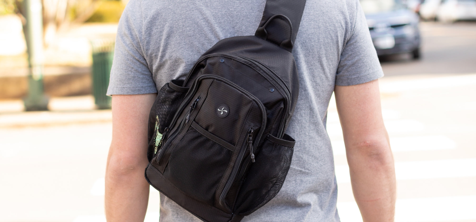 A man in grey t-shirt wearing the black Sugar Medical Diabetes Sling Backpack on his back.