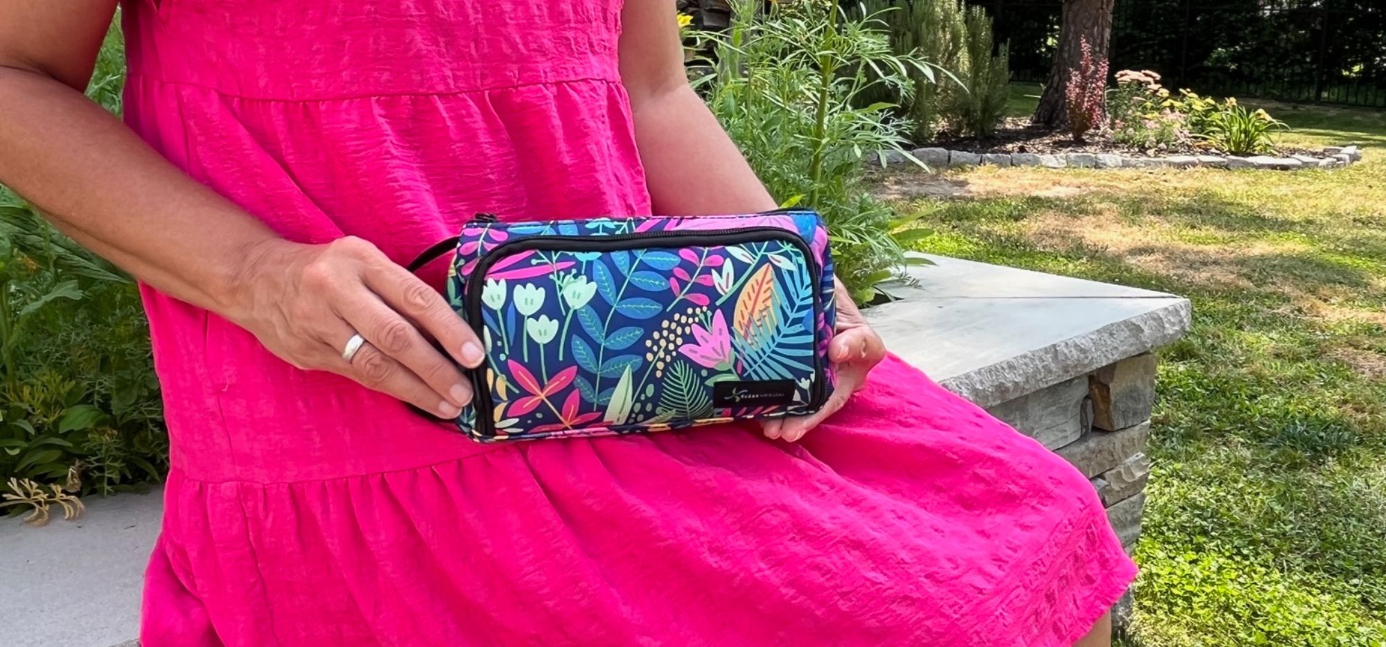Women in pink dress sitting holding a blue floral Insulated Insulin Pen Case on her lap.