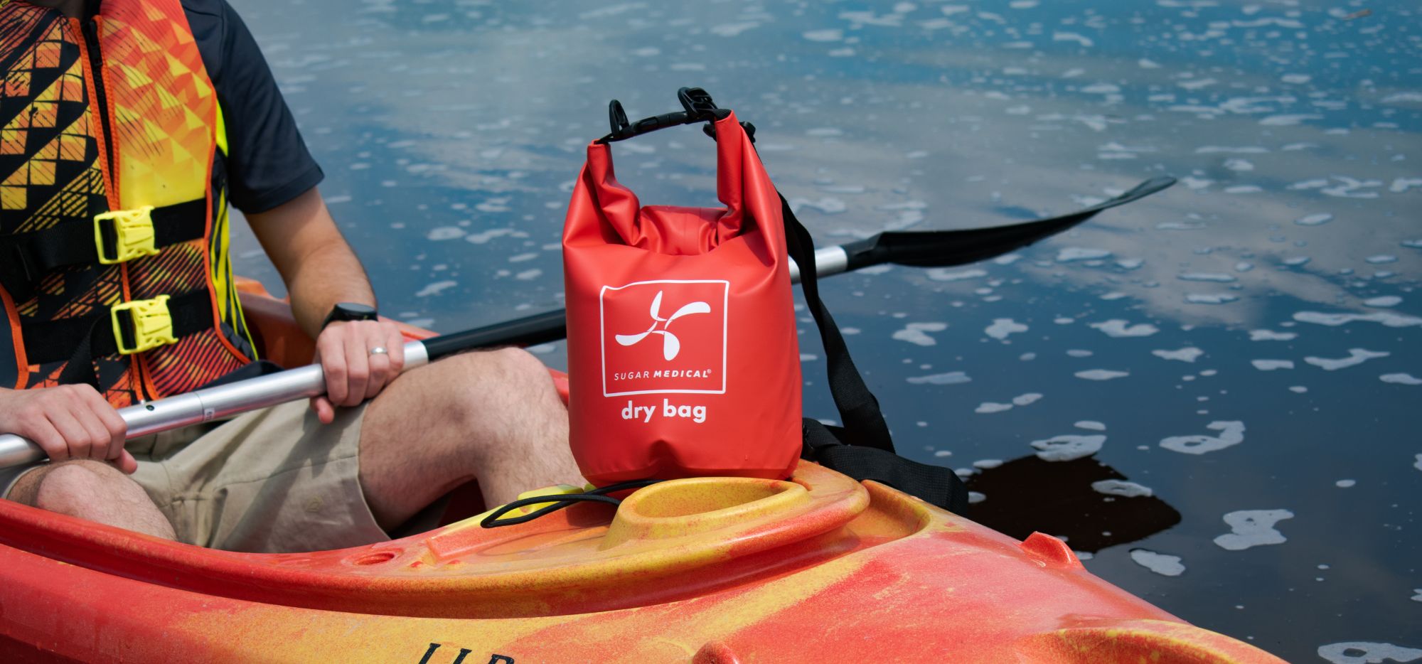 A man sitting in a kayak with a Sugar Medical Dry Bag on it.