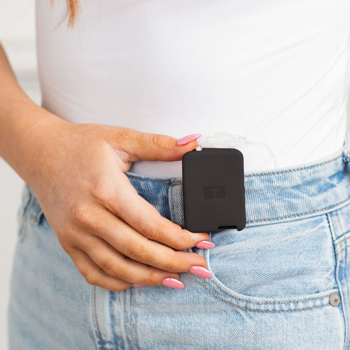 Girl wearing a white tee, with a black Tandem Mobi EZ-To-Charge Clip attached to the front waistband of her jeans.