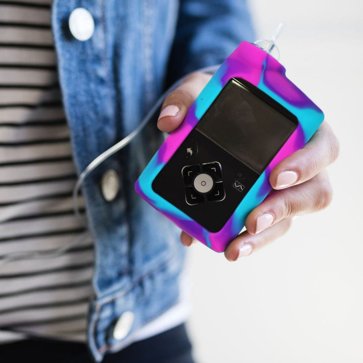 Women holding pink, blue and purple tie-dye Medtronic Insulin Pump Gel Skin with Medtronic pump in it.