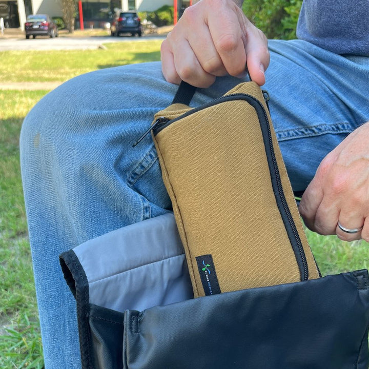 Man pulling out brown Hamilton Diabetes Supply case out of black backpack with his hand on the handle.