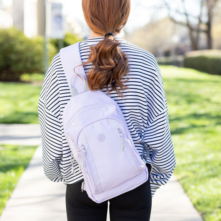 Girl with stripe top wearing the light purple Insulated Roam Sling Backpack on her back.