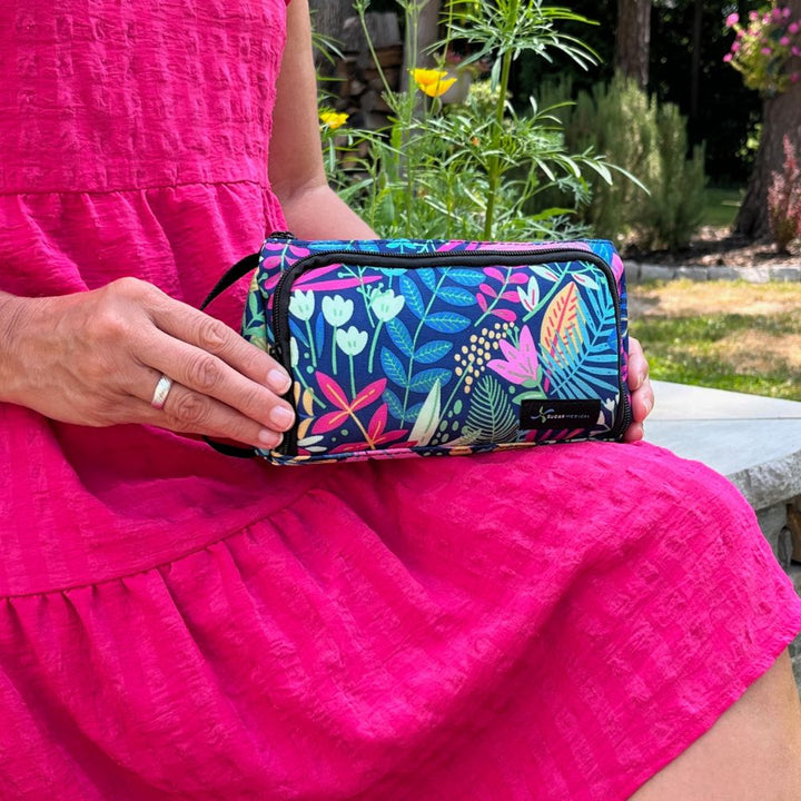 A blue floral pattern Insulated Diabetes Insulin Supply Case with black handle on the side in a women's lap.