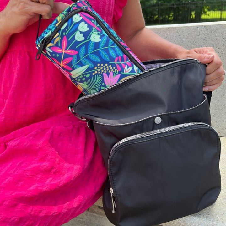A women sitting pulling the blue floral pattern Insulated Diabetes Insulin Supply Case out of a black backpack by handle.