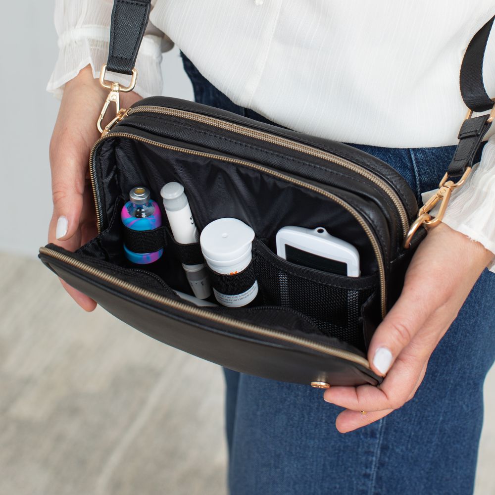 Diabetic supplies neatly organized in the front compartment of the Black Essential Diabetes Purse, including items like test strips, lancets, and alcohol wipes secured in elastic loops and mesh pockets.