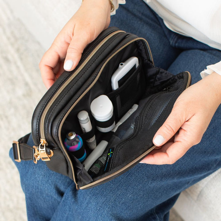 Diabetic supplies neatly organized in the front compartment of the Black Essential Diabetes Purse, including items like test strips, lancets, and alcohol wipes secured in elastic loops and mesh pockets.