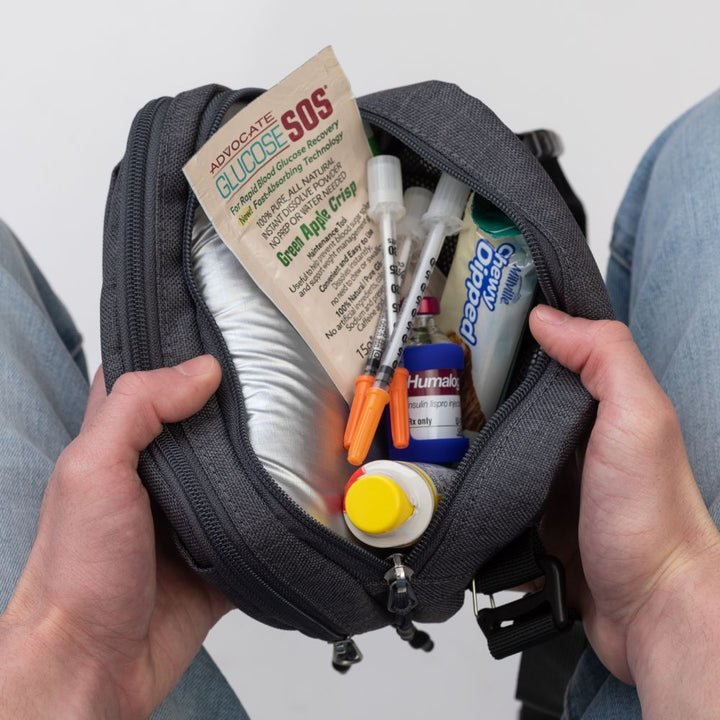 Diabetes Insulated Convertible Belt Bag in Grey opened in man's lap showing insulated pocket with diabetes supplies in it.
