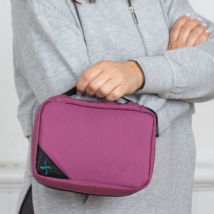 Women in grey top holding the Orchid Insulated Diabetes Organizer by the handle in one hand.