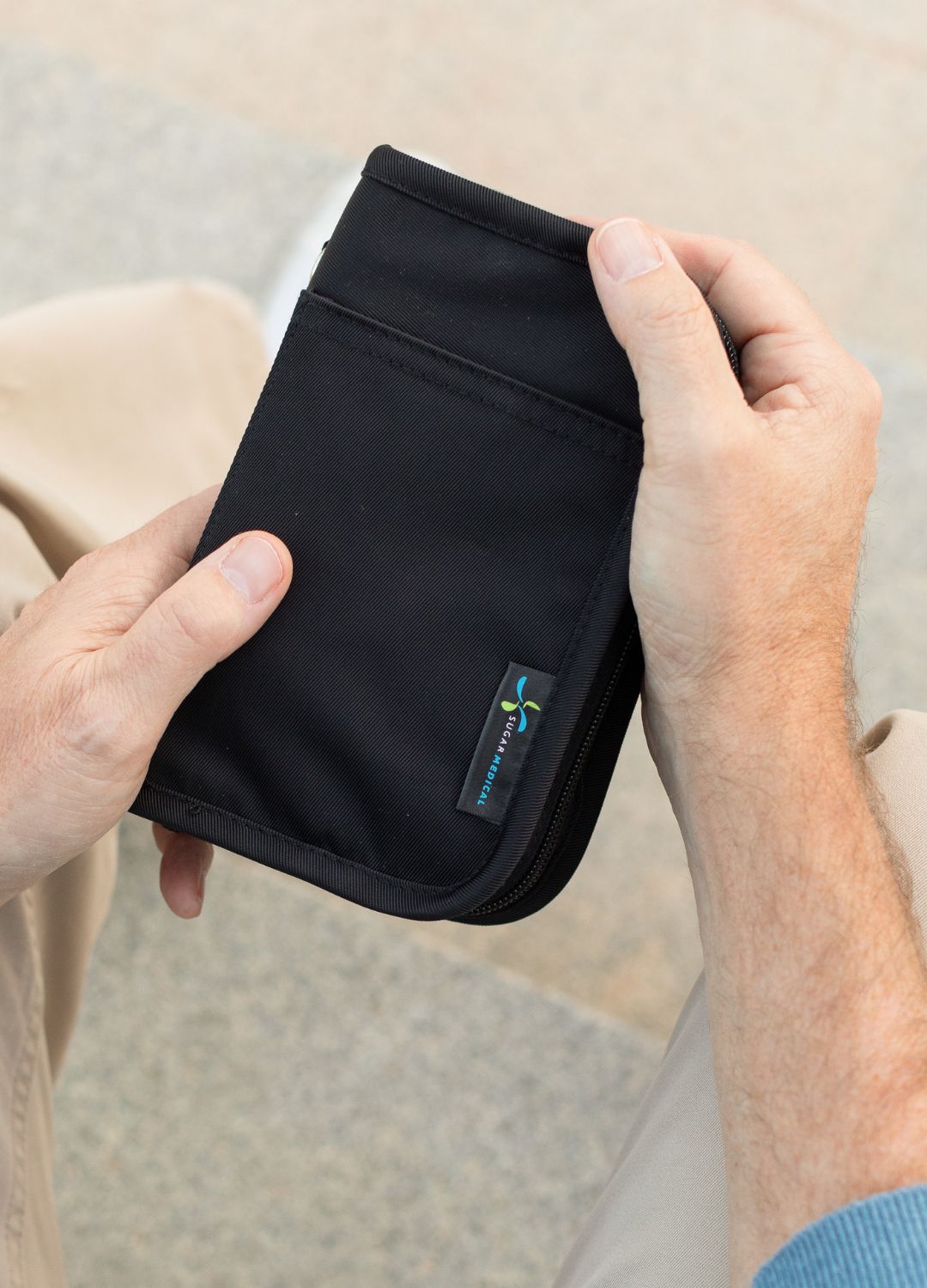 Man sitting down holding black diabetes supply case II in hands.