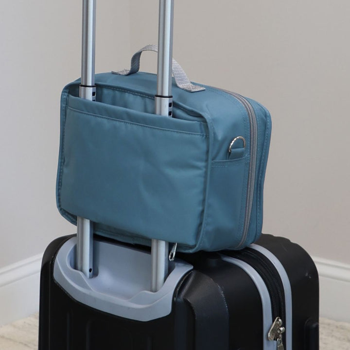 Diabetes Insulated Travel Bag in steel blue carried on a suitcase and being held by the handle.