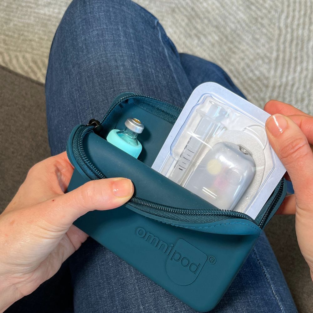 Person holding a teal Omnipod device case with a pod inside.