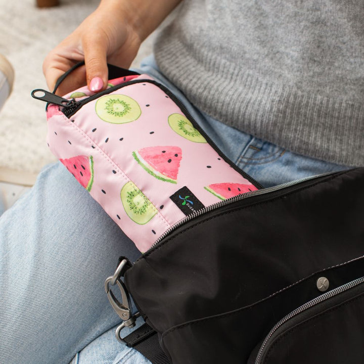 A women sitting pulling the pink watermelon pattern Insulated Diabetes Insulin Supply Case out of a black backpack by handle.