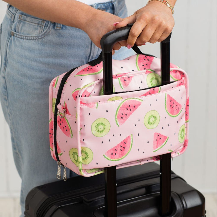 Diabetes Insulated Travel Bag in pink watermelon print carried on a suitcase and being held by the handle.