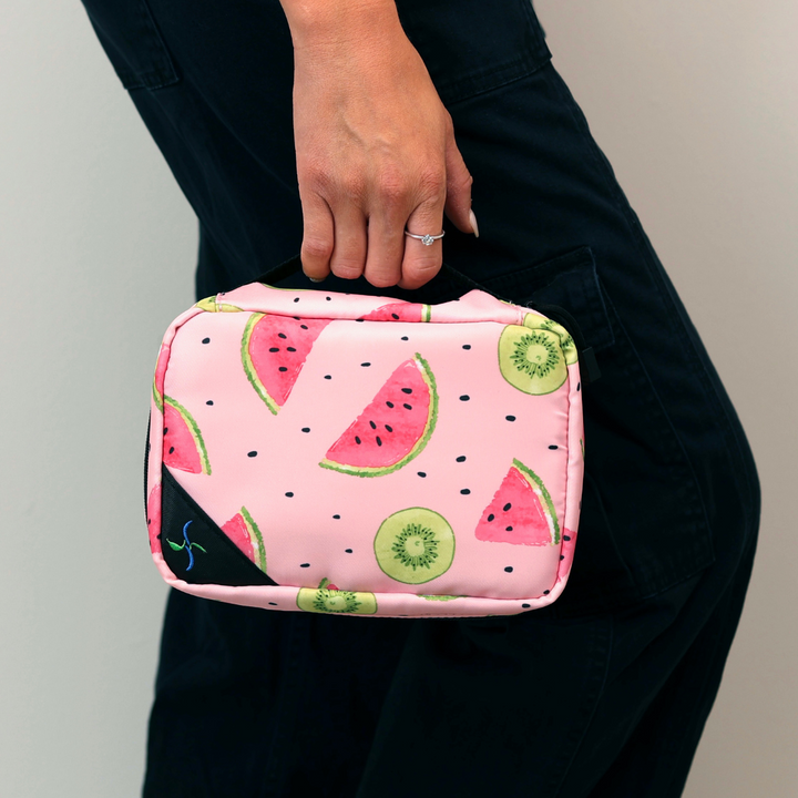 Women with black pants holding the Watermelon Insulated Diabetes Organizer by the handle in one hand.