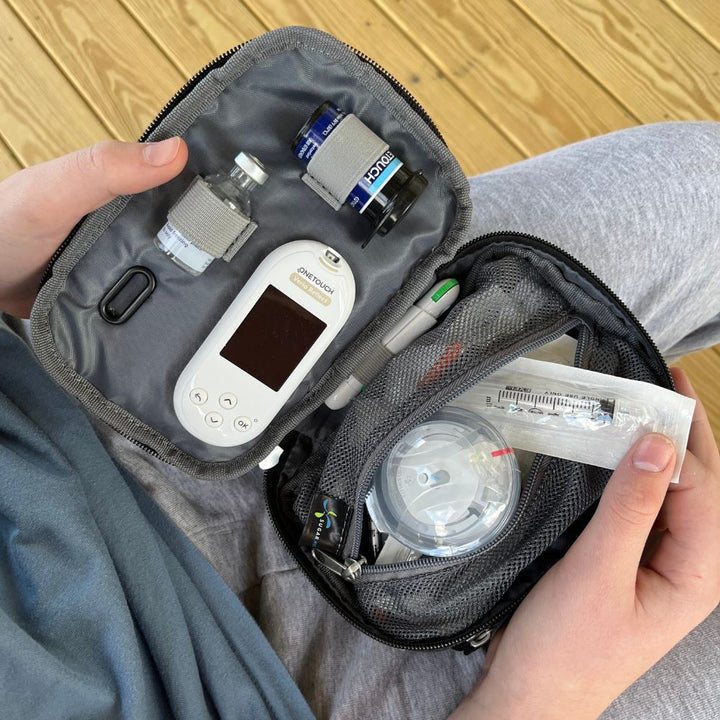 Tandem Supply Case in blue, grey and black opened in the boy's lap with an inside set up containing diabetic supplies while pulling out Tandem supplies.