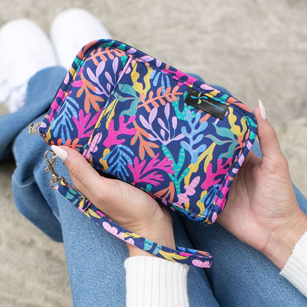 Women holding a navy with bright color diabetes supply case in her lap.