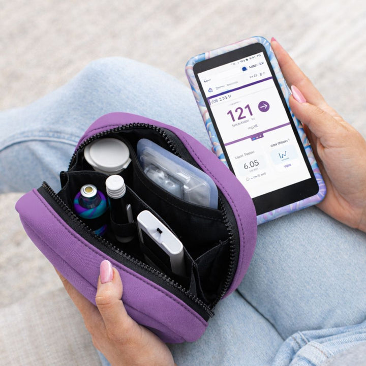 Purple travel case with medical supplies and a smartphone displaying a Omnipod 5.