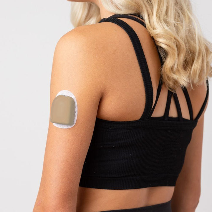 A woman wearing a caramel PumpPOP on the outside of her upper left arm