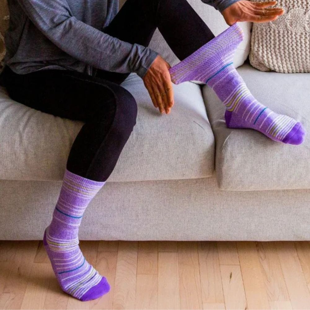 Two legs wearing Dr. Segal purple stripes socks.