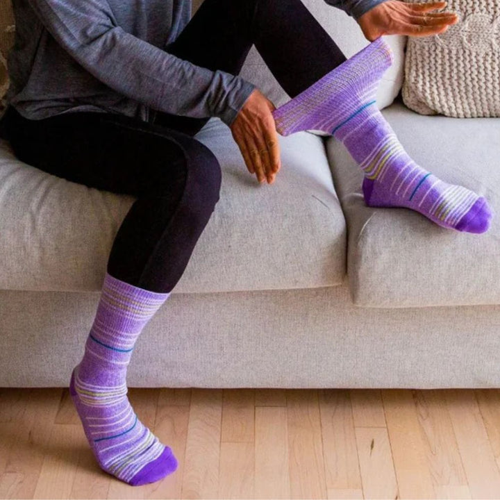 Two legs wearing Dr. Segal purple stripes socks.