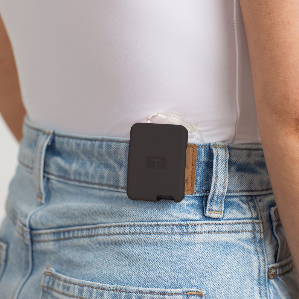 Girl wearing a white tee, with a black Tandem Mobi EZ-To-Charge Clip attached to the back waistband of her jeans. 