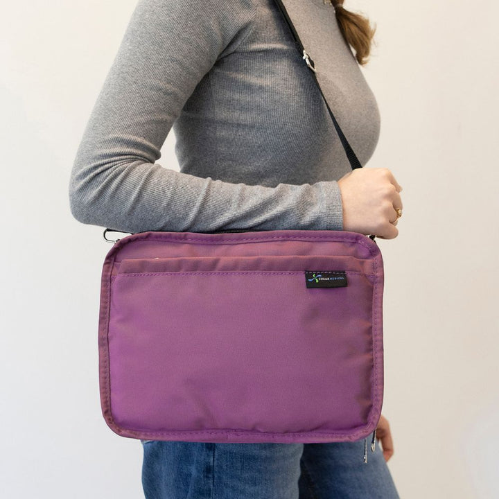 Women in grey top wearing orchid insulated diabetes travel bag on her shoulder, highlighting its grey shoulder strap. 