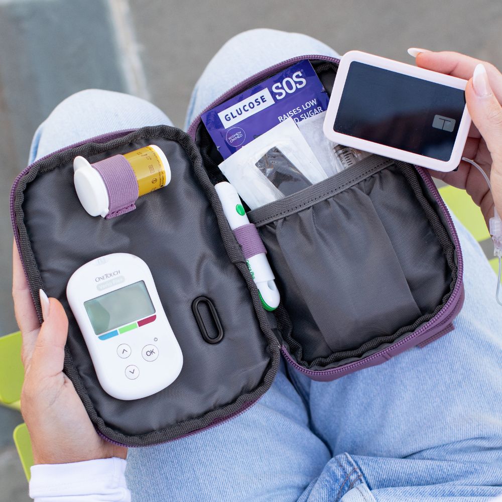 The Misty Purple Diabetes Insulated Convertible Supply Bag open on a women lab with Tandem supplies organized in the pockets and women holding a Tandem pump with Sugar Medical gel skin in her hand. 