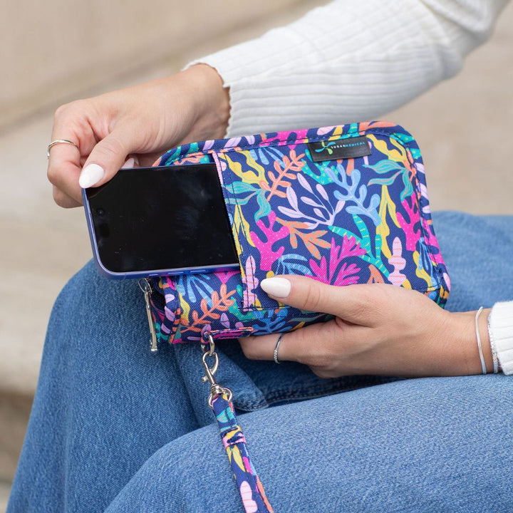 Women holding a diabetes supply case on her lap pulling a phone out of the front pocket. 