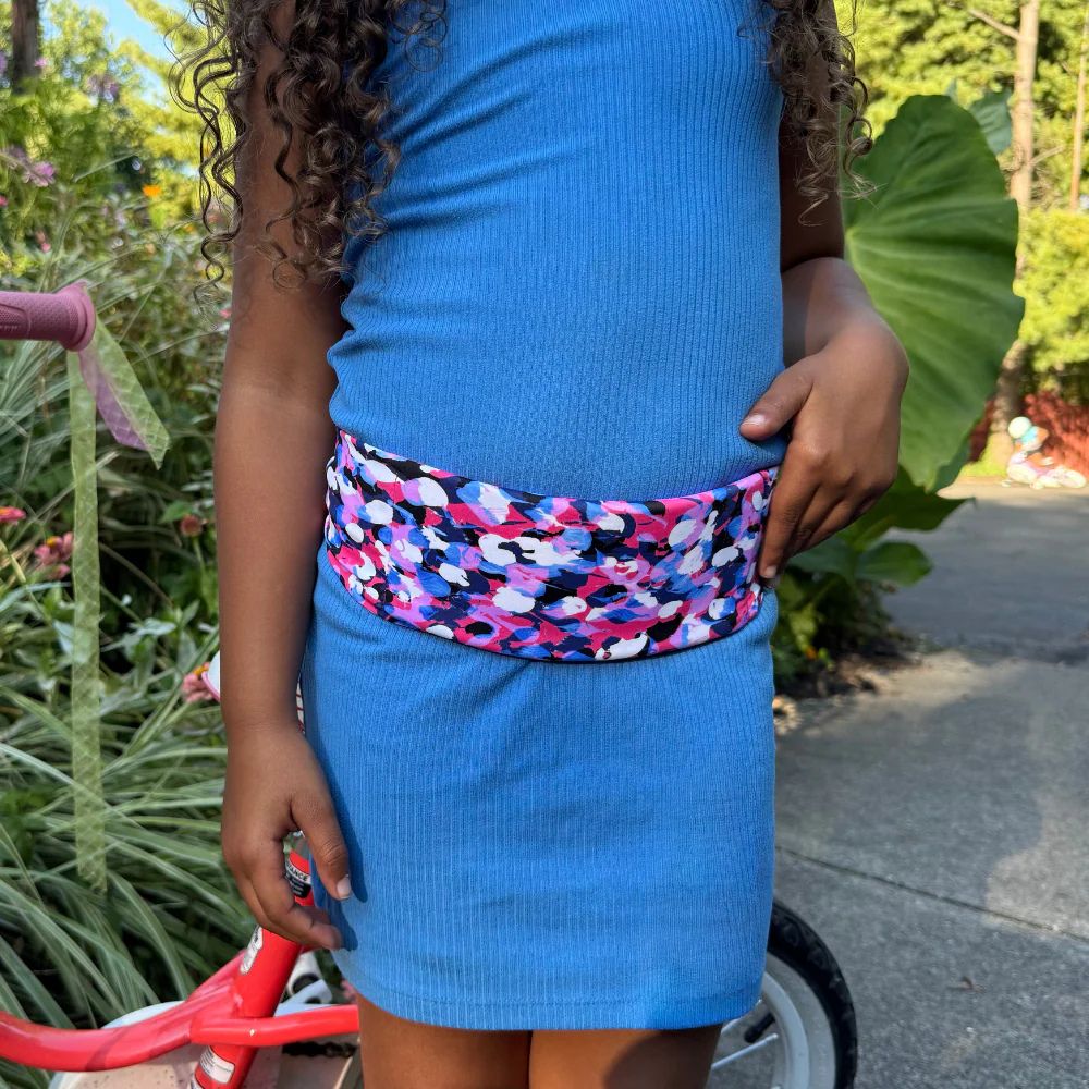 Girl wearing a kids' bubbles Bandi Wear Pocket Belt, pulling a phone out of the pocket, highlighting its practical design for carrying essentials.