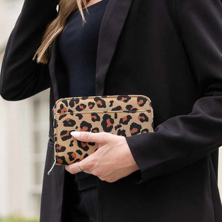 A person in a black blazer holds a leopard-print zip-around diabetes supply case with a silver zipper pull.