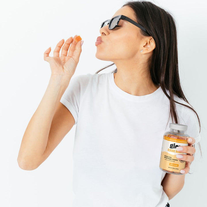 Woman in white top holding a glow glucose bottle with a blurred background