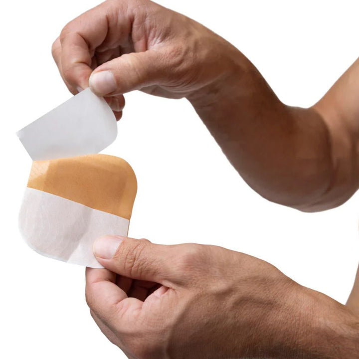 Close-up of hands peeling the backing off a tan Skin Grip patch, preparing to apply