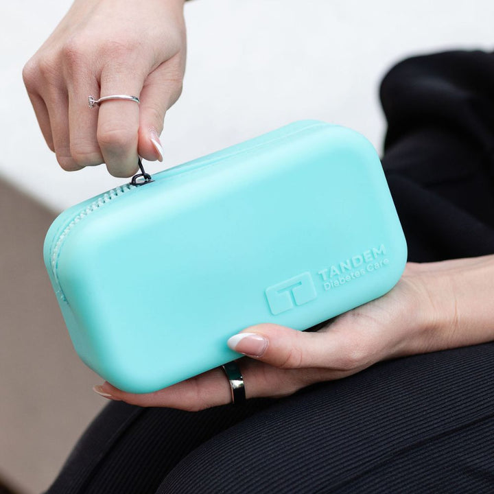 Aqua carrying case with a brand logo held by a person.