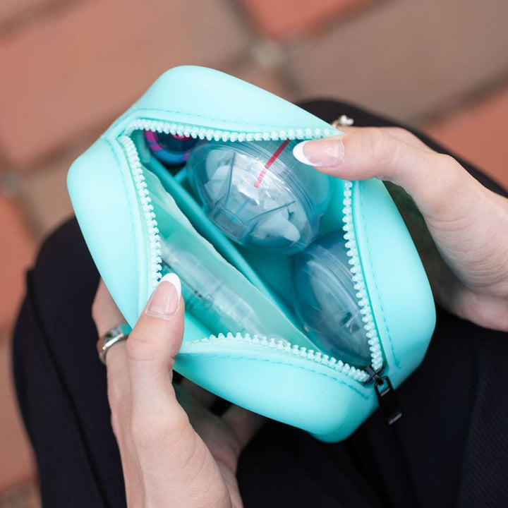 Aqua zippered case containing Tandem supplies and insulin vial, held by a person.