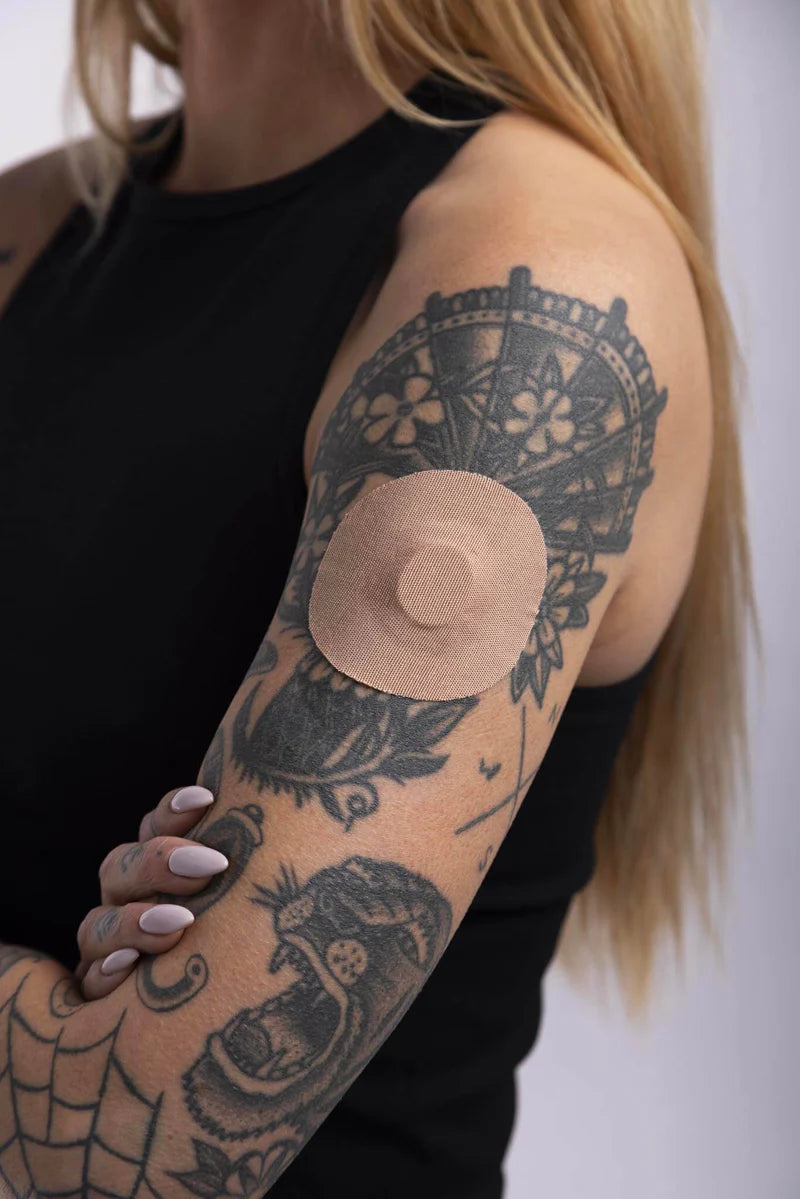 Dexcom G7 sensor secured with a tan Skin Grip patch on a woman’s upper arm—showing full coverage, secure fit, and comfortable wear in a real-life setting.