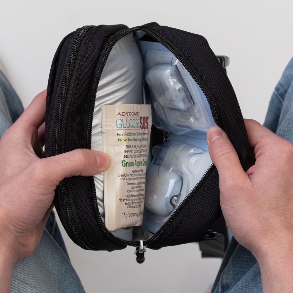 Diabetes Insulated Convertible Belt Bag in Black  opened in a man's lap showing insulated pocket with Omnipod pump supplies in it. 