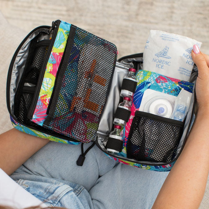 Women pulling out an ice pack in the Butterly Insulated Organizer open on her lap with diabetes supplies organized in it. 