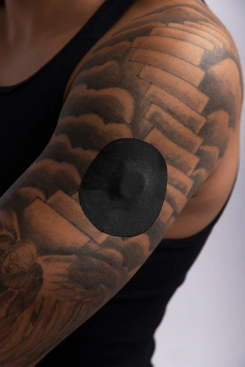 Dexcom G7 sensor secured with a black Skin Grip patch on a woman’s upper arm—showing full coverage, secure fit, and comfortable wear in a real-life setting.