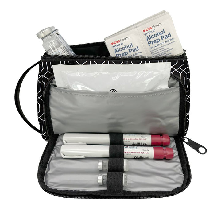An open black and white geometric patterned medical travel kit pouch containing a glass vial, an Alcohol Prep Pad from OPI Health, gauze, and three insulin pens on a white background.