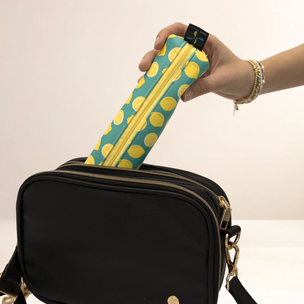Hand holding a black bag with a yellow and blue lemon design MedMate against a plain background