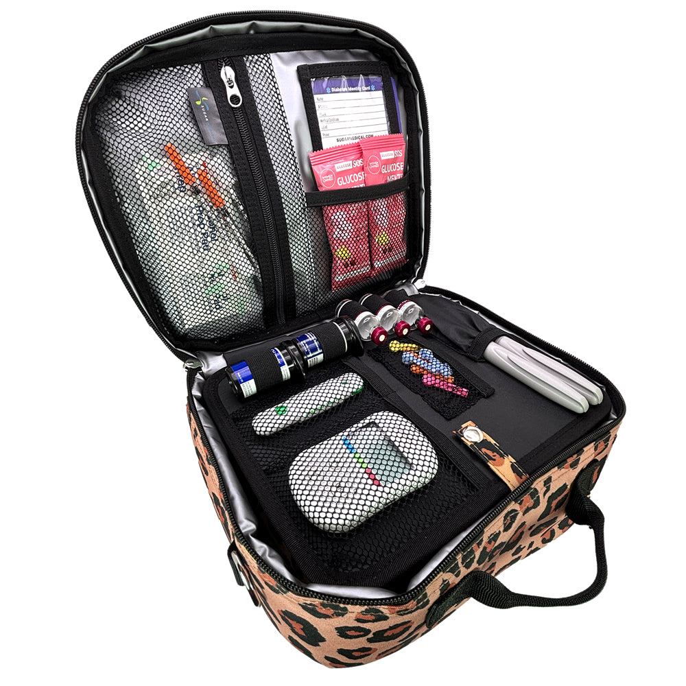 An open leopard-print carrying case with black mesh and fabric compartments, insulin pens, glucose meter, and other diabetes supplies, photographed on a plain white background.