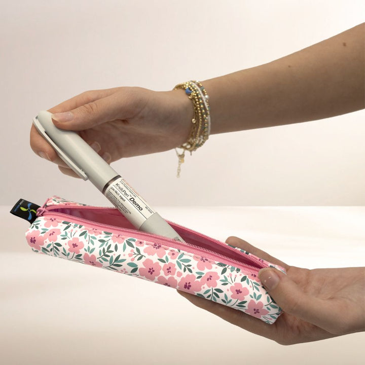 Hand holding a floral MedMate with a pen, against a plain background