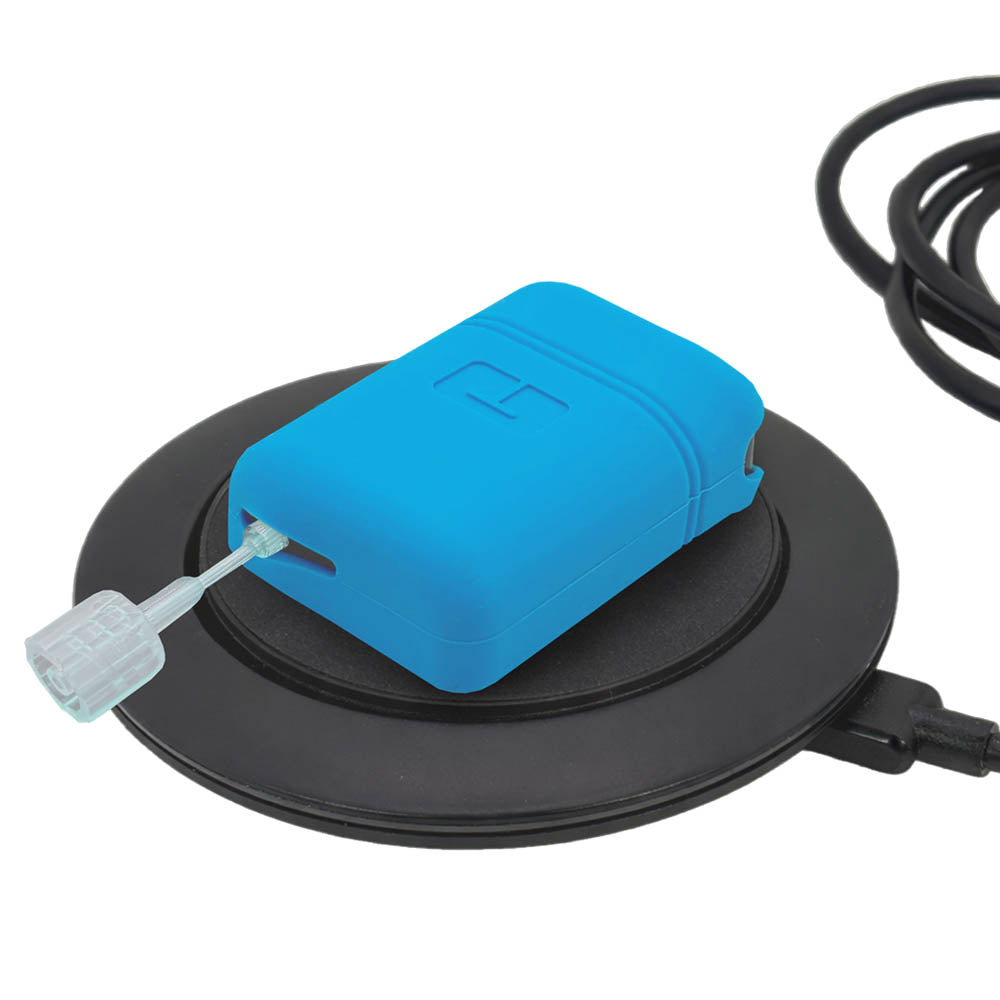 Mobi insulin pump with blue gel skin resting on a circular charging base against a white background