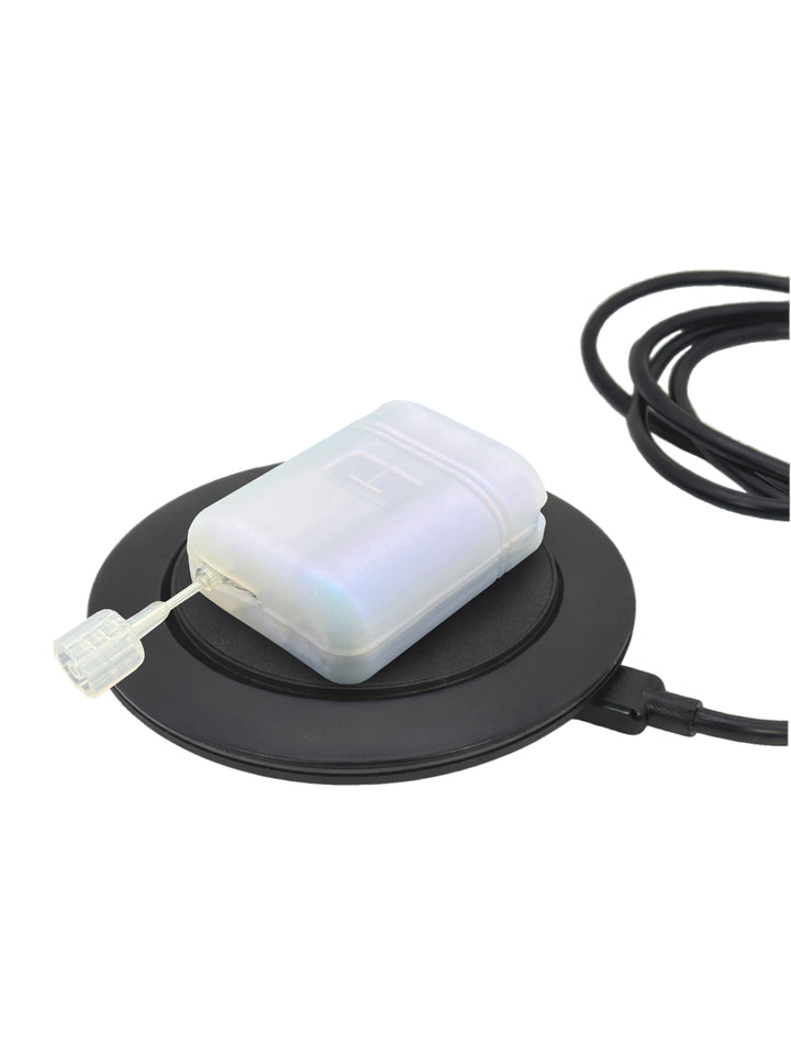 Mobi insulin pump with white gel skin resting on a circular charging base against a white background