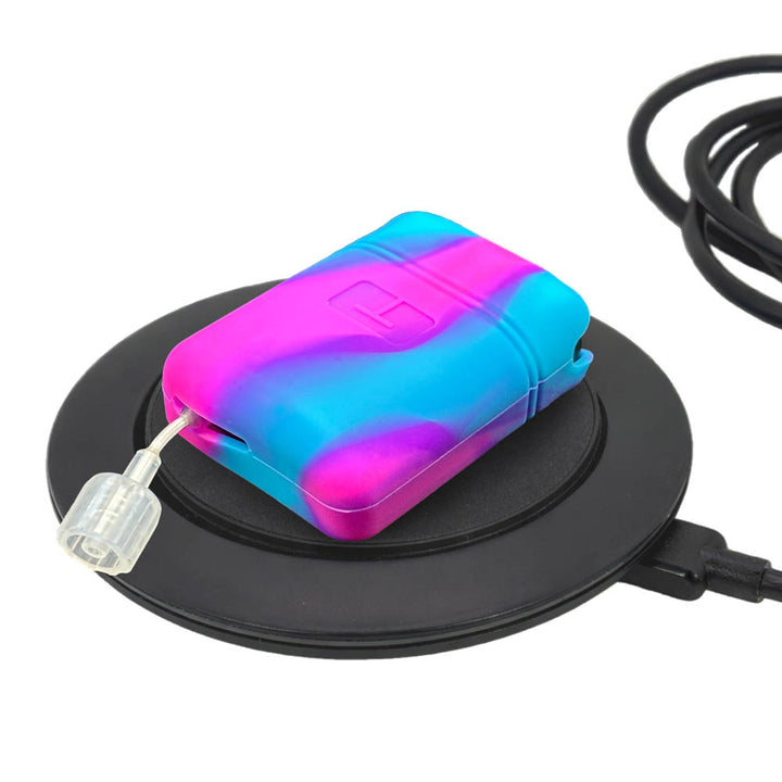 Mobi insulin pump with pink and blue gel skin resting on a circular charging base against a white background