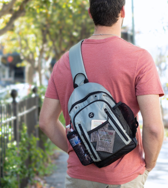 Sugar Medical Insulated Diabetes Sling Backpack in light grey on man's back with glucose SOS in the front mesh pocket. 