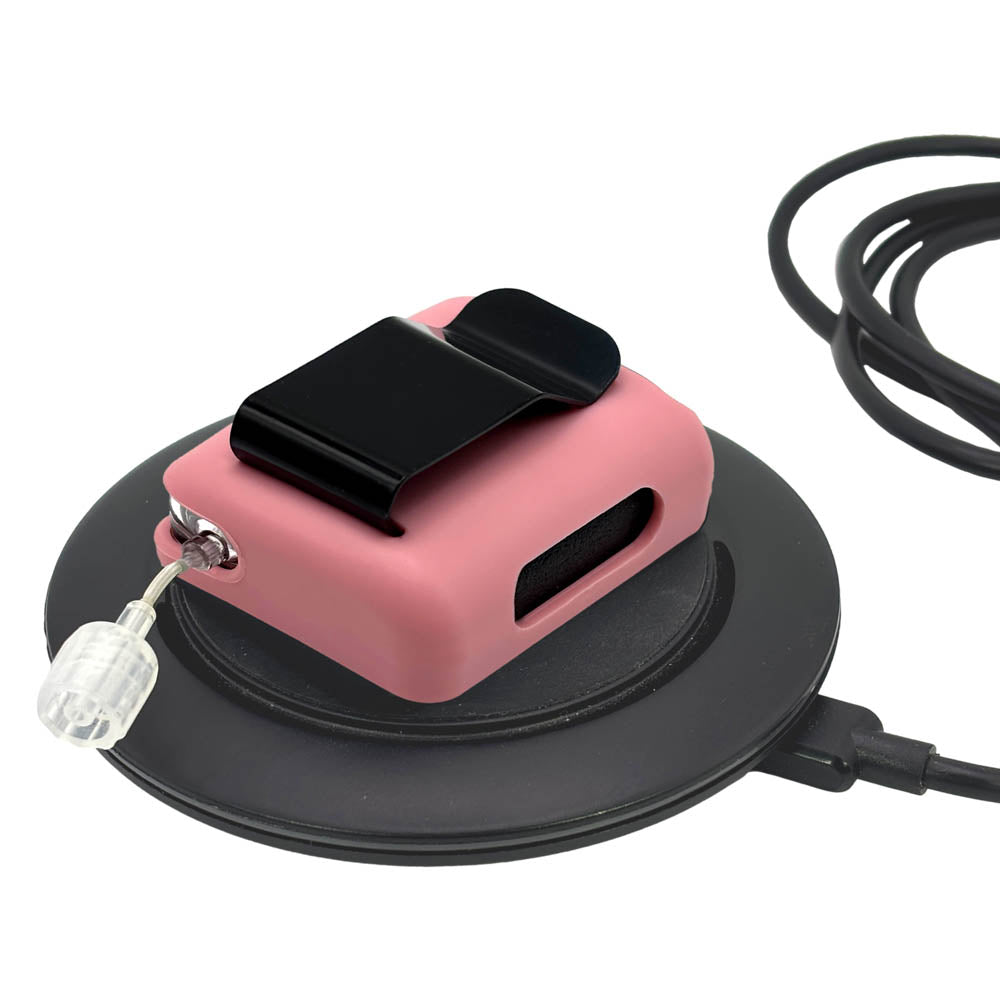 Pink Tandem Mobi EZ-To-Charge Clip with Mobi insulin pump inside the case, lying flat on a charger.